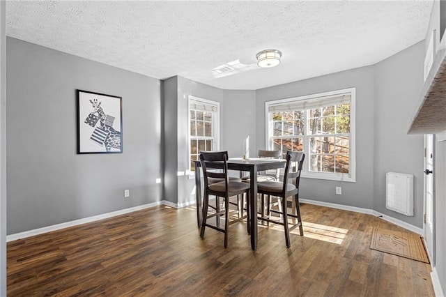 dining space with a textured ceiling and dark hardwood / wood-style flooring