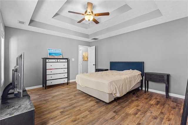 bedroom featuring a raised ceiling, ceiling fan, and dark hardwood / wood-style flooring