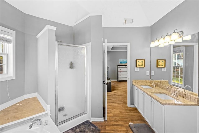 bathroom with lofted ceiling, a healthy amount of sunlight, wood-type flooring, and walk in shower