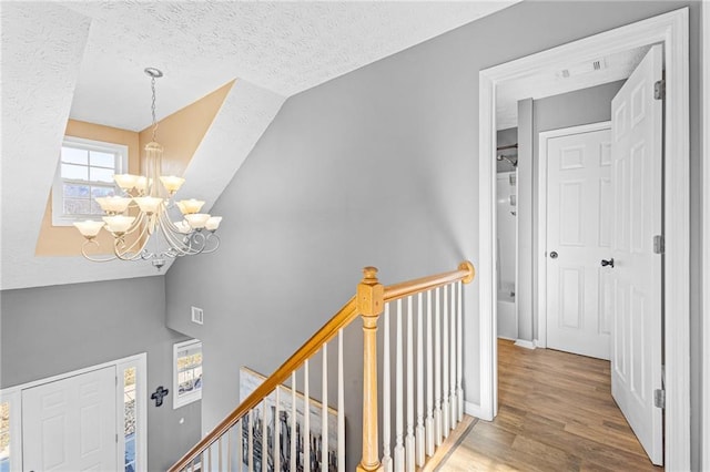 interior space featuring wood-type flooring, vaulted ceiling, a textured ceiling, and an inviting chandelier