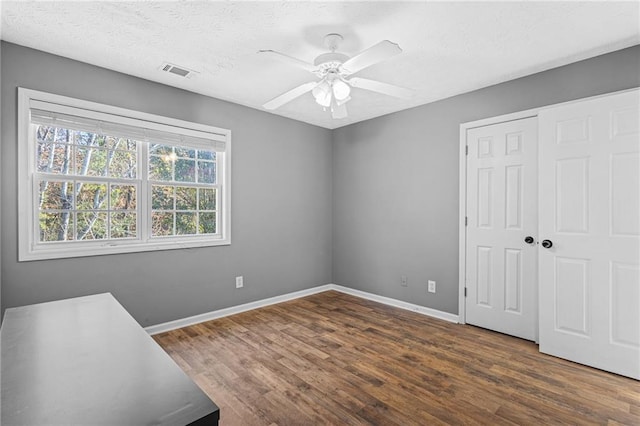 interior space featuring a textured ceiling, a closet, dark hardwood / wood-style floors, and ceiling fan