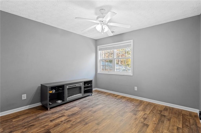 spare room with a textured ceiling, ceiling fan, and dark hardwood / wood-style floors