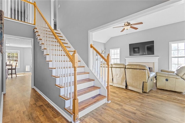 staircase with hardwood / wood-style floors, ceiling fan, and lofted ceiling