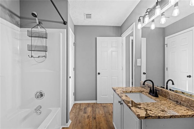 bathroom featuring shower / washtub combination, hardwood / wood-style floors, vanity, and a textured ceiling