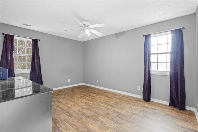 empty room with hardwood / wood-style floors, ceiling fan, and a textured ceiling