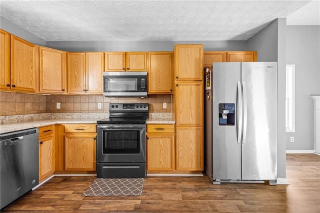 kitchen featuring a textured ceiling, stainless steel appliances, tasteful backsplash, and dark wood-type flooring