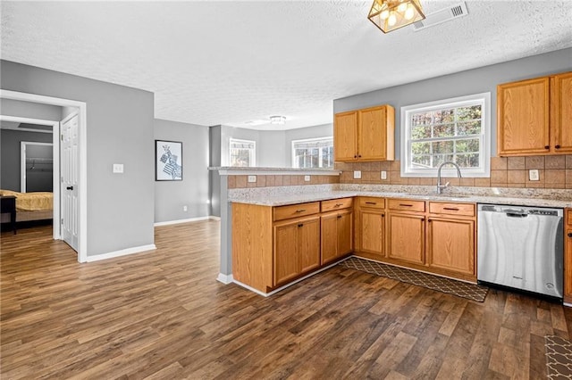 kitchen featuring dishwasher, dark wood-type flooring, sink, a textured ceiling, and kitchen peninsula