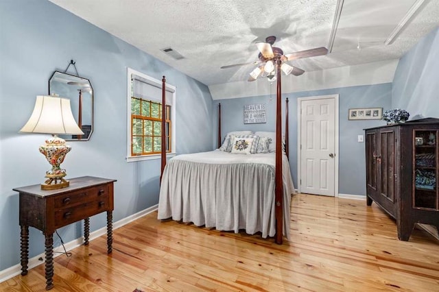 bedroom with ceiling fan, light hardwood / wood-style floors, and a textured ceiling