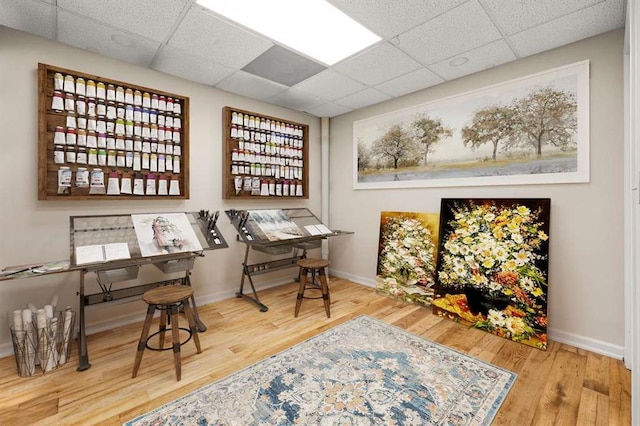 living area featuring a paneled ceiling and wood-type flooring