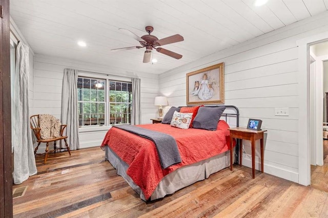 bedroom featuring ceiling fan, hardwood / wood-style floors, and wood walls