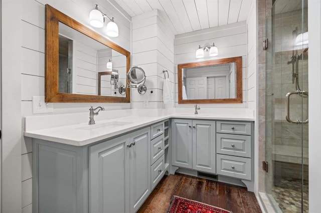 bathroom with a shower with shower door, wooden walls, vanity, and wood-type flooring