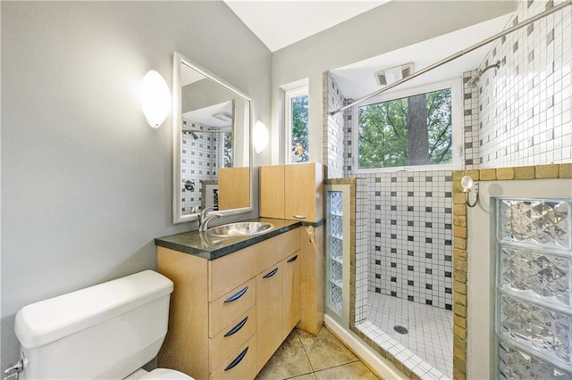 bathroom with a tile shower, tile patterned flooring, vanity, and toilet