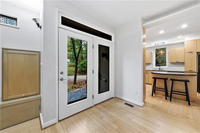 doorway to outside with sink and light hardwood / wood-style floors