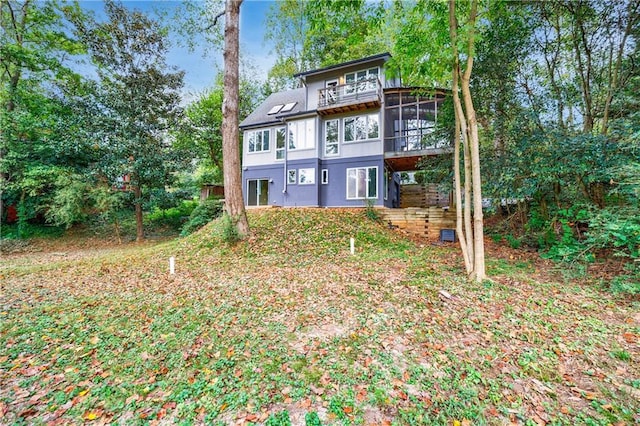 rear view of property with a sunroom and a balcony