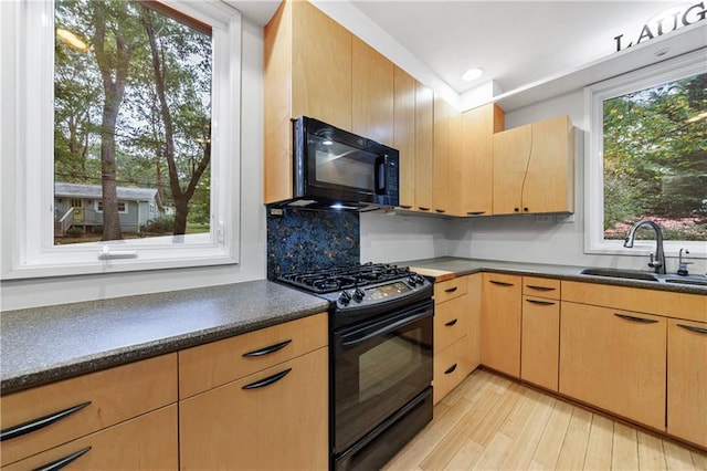 kitchen with light wood-type flooring, light brown cabinetry, sink, and black appliances