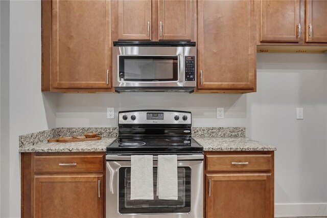 506 Tallapoosa Trl, Woodstock, GA 30188 - kitchen with stainless steel appliances, light stone counters, baseboards, and brown cabinets