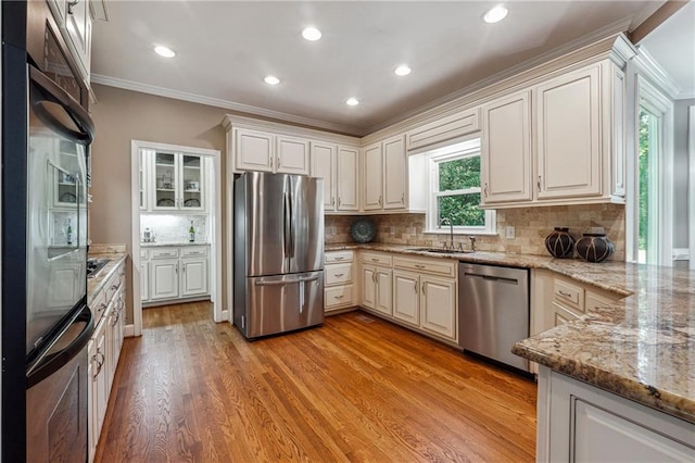 kitchen with light wood-type flooring, sink, white cabinetry, stainless steel appliances, and crown molding