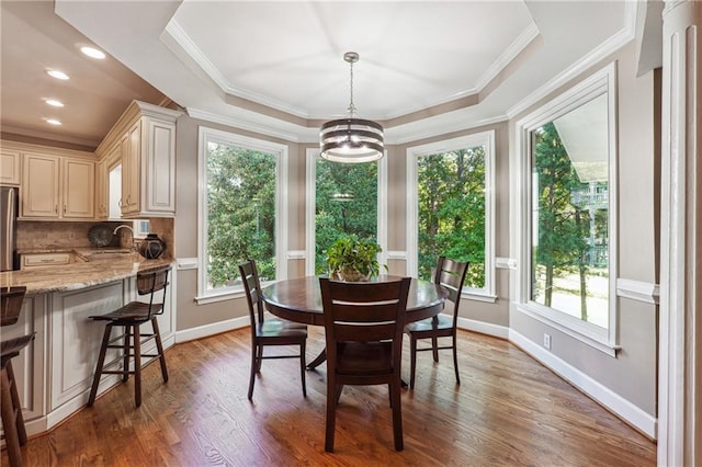 dining area featuring a notable chandelier, a tray ceiling, hardwood / wood-style floors, and plenty of natural light