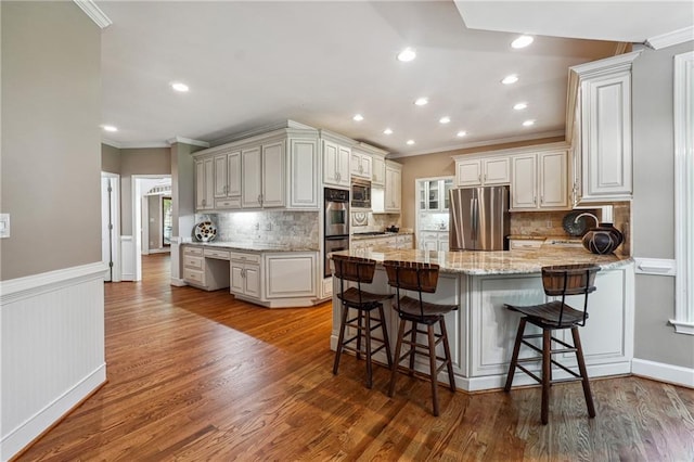 kitchen featuring light stone counters, light hardwood / wood-style floors, a breakfast bar area, kitchen peninsula, and appliances with stainless steel finishes