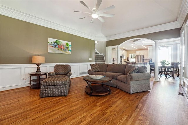 living room with wood-type flooring, ceiling fan, decorative columns, and crown molding