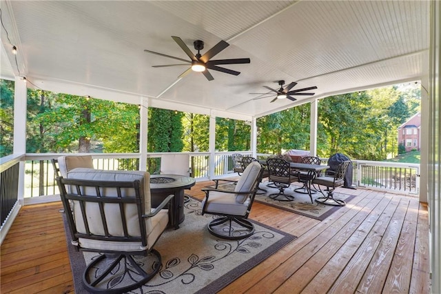 wooden deck with ceiling fan and a fire pit