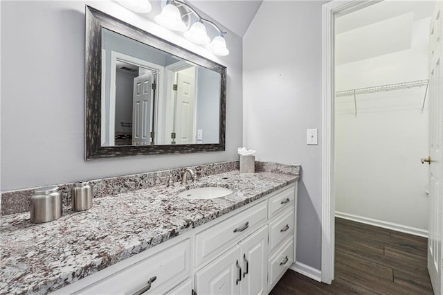 bathroom with wood-type flooring, lofted ceiling, and vanity