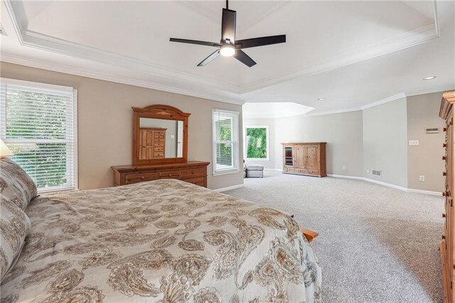 carpeted bedroom with ceiling fan, a skylight, a tray ceiling, and crown molding