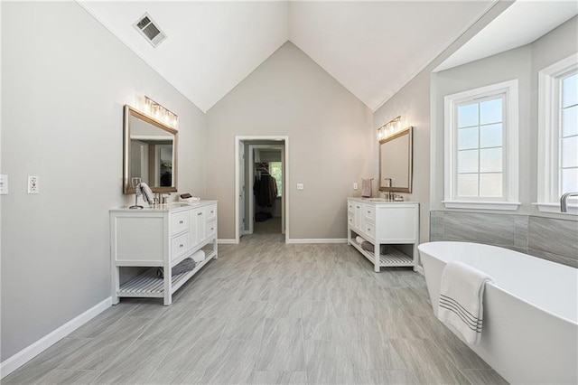 bathroom with lofted ceiling, hardwood / wood-style floors, a bath, and vanity