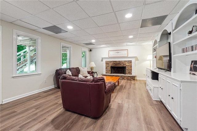 living room featuring light hardwood / wood-style flooring, a fireplace, and a paneled ceiling