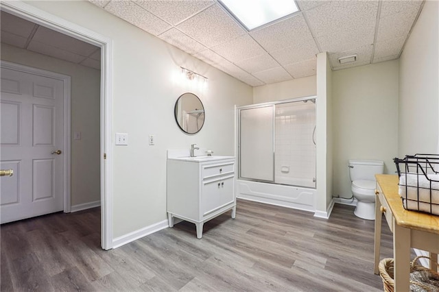 full bathroom with vanity, toilet, a paneled ceiling, bath / shower combo with glass door, and hardwood / wood-style floors