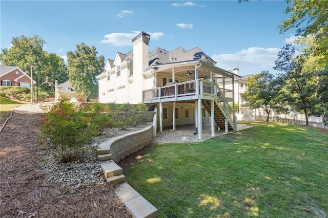 back of house featuring a lawn, a wooden deck, ceiling fan, and a patio area