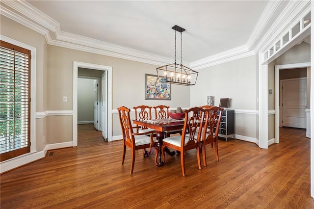 dining space featuring ornamental molding, a chandelier, and hardwood / wood-style flooring