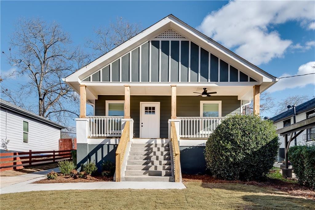 view of front of house featuring covered porch, ceiling fan, and a front yard