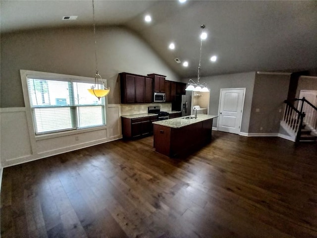 kitchen with dark brown cabinets, dark wood finished floors, pendant lighting, an island with sink, and appliances with stainless steel finishes