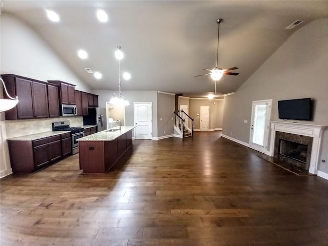 kitchen with a sink, dark brown cabinets, open floor plan, appliances with stainless steel finishes, and dark wood-style flooring