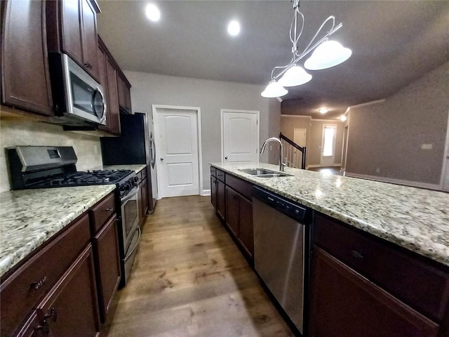 kitchen with a sink, light stone counters, dark wood finished floors, appliances with stainless steel finishes, and dark brown cabinets