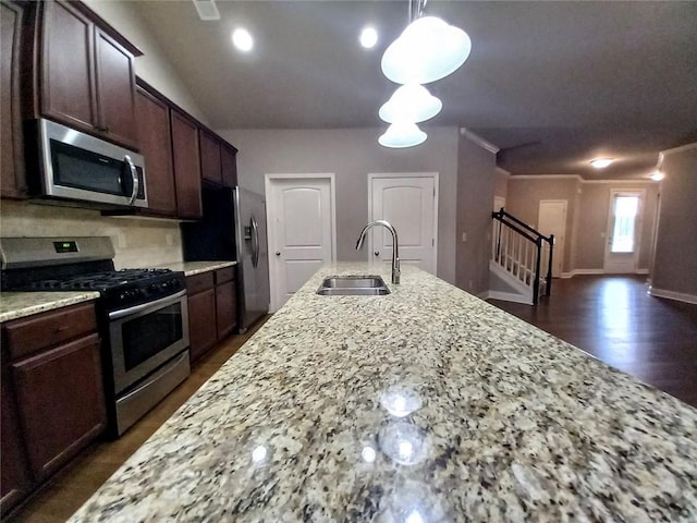 kitchen featuring light stone counters, a sink, ornamental molding, dark brown cabinetry, and stainless steel appliances