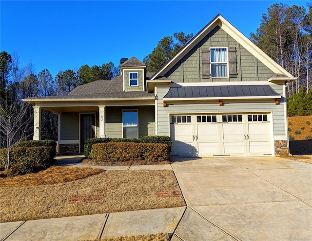 craftsman-style house featuring stone siding, concrete driveway, a standing seam roof, and metal roof