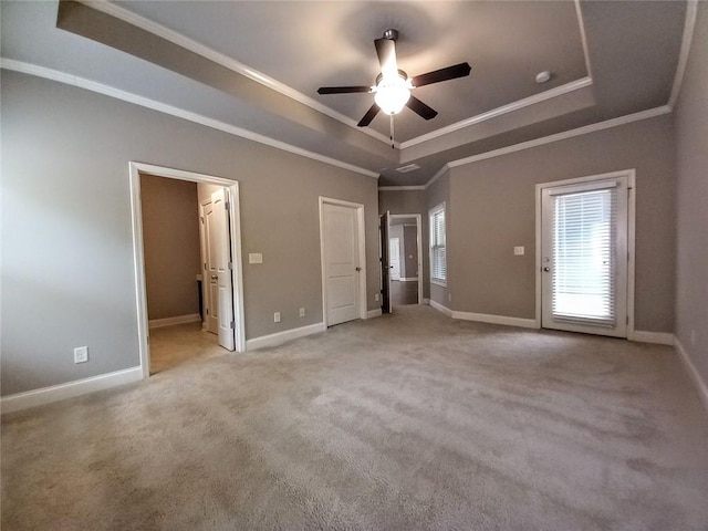 unfurnished bedroom featuring ornamental molding, baseboards, a tray ceiling, and carpet floors