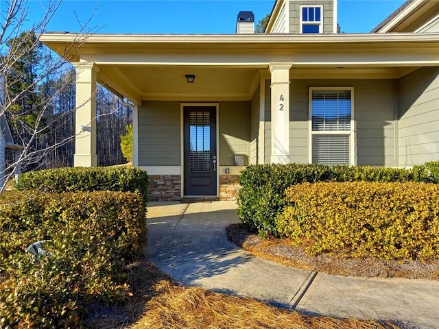 doorway to property featuring stone siding and covered porch