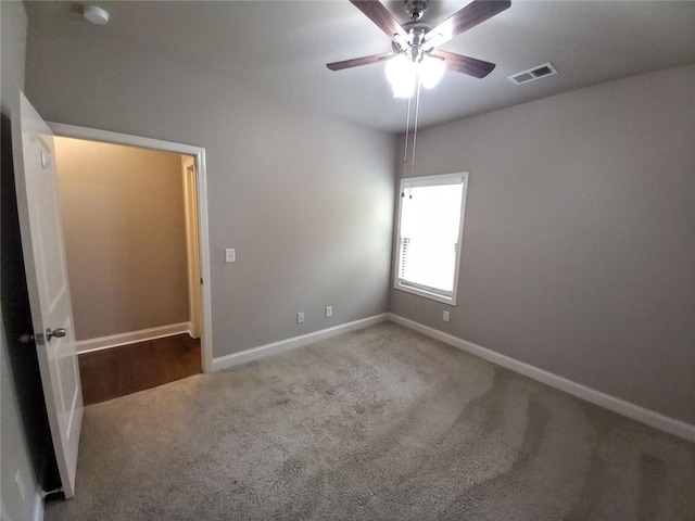 carpeted empty room featuring visible vents, ceiling fan, and baseboards