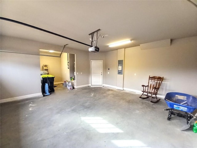 garage featuring electric panel, a garage door opener, and baseboards