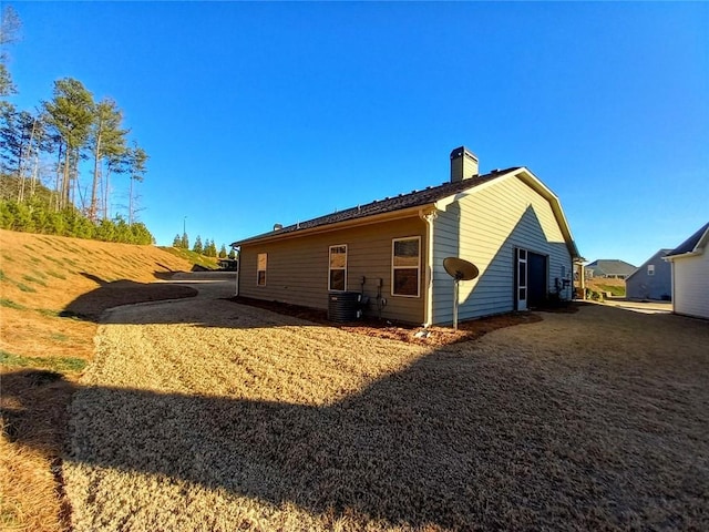 back of property with central AC unit and a chimney