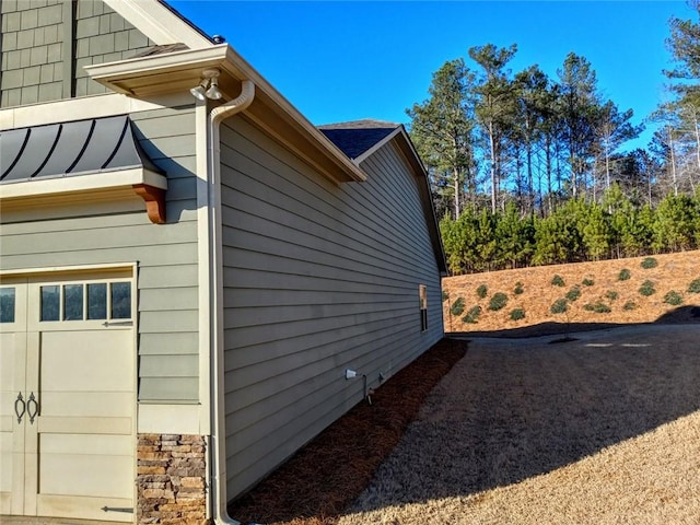 view of side of home featuring a garage and stone siding