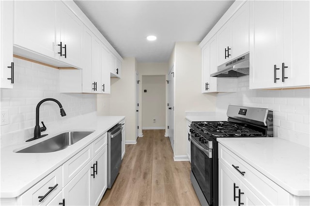 kitchen with sink, light hardwood / wood-style flooring, appliances with stainless steel finishes, white cabinetry, and tasteful backsplash