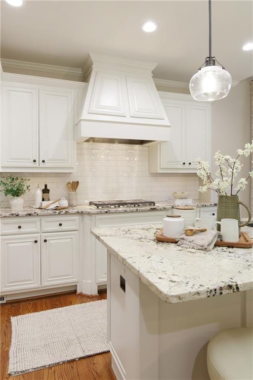 kitchen featuring stainless steel gas stovetop, premium range hood, light wood finished floors, and white cabinetry