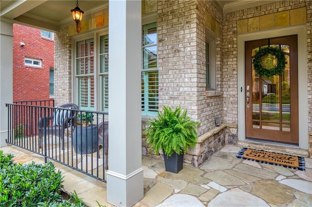 property entrance with a porch and brick siding