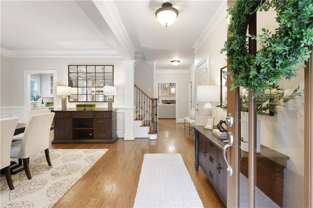 foyer featuring stairway, crown molding, wainscoting, and light wood-type flooring