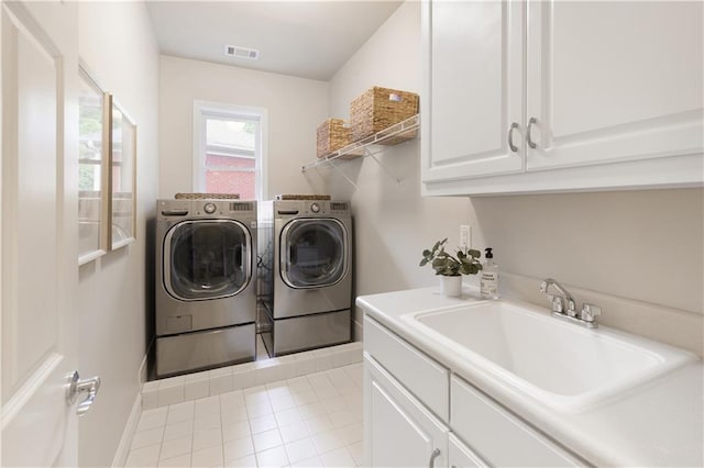 washroom featuring visible vents, washing machine and dryer, cabinet space, a sink, and light tile patterned flooring