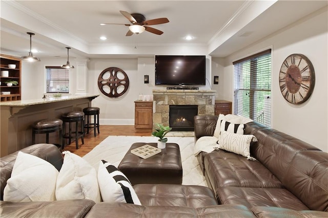living room with light wood-style floors, crown molding, baseboards, and ceiling fan